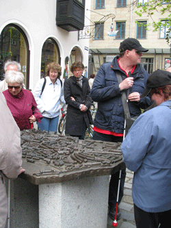 Die Gruppe ertastet die Konturen Nürnbergs auf dem taktilen Stadtplan vor dem Fembo-Haus.