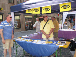 unser Infostand - zu sehen ist die Auslage an Broschueren, eine Schautafel, Standbetreuer. 